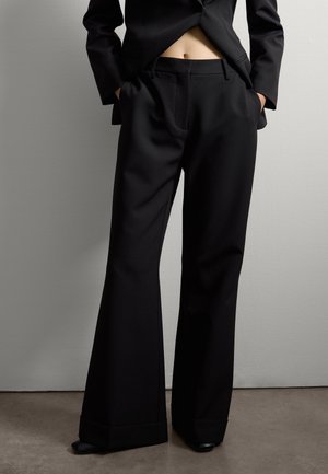 Black tailored trousers with a wide-leg design, made from smooth fabric, featuring side pockets and folded hems.