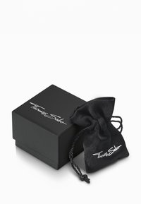 Scatola regalo nera con logo bianco "Thomas Sabo", accompagnata da una borsa in satin nera con chiusura a cordoncino. Texture liscia, forma rettangolare.