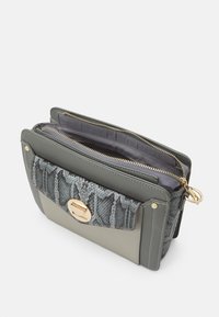 Borsa grigia con stampa a serpente nella parte frontale, hardware dorato e doppi scomparti con zip. Texture morbida, forma rettangolare e design con pannelli a contrasto.