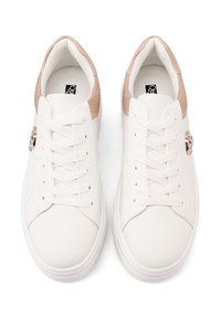 Sneaker bianco con una tomaia in pelle liscia, accenti beige testurizzati, lacci piatti e un logo metallico decorativo sul lato.