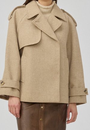 Beige wollen peacoat met brede revers en met knoopgespen op de manchetten, gedragen over een crème gebreide coltrui en een bruine leren rok.