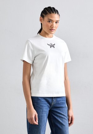 White cotton t-shirt with short sleeves, featuring a black logo design on the chest. Paired with blue denim jeans.