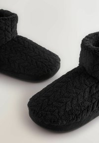 Mustad mustad sussid tekstureeritud pinnaga ja madala, kokkuvolditava äärisega. Ümar toe disain ja pehme, pehmendusega tald.