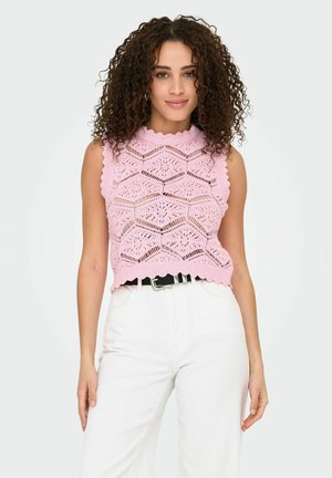Lichtroze gebreide crop top met scalloped randen en een geometrisch opengewerkte patroon, gecombineerd met witte hoge taille broek en een zwarte riem.