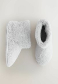 Valkoiset pehmeät tohvelit, joissa pehmeä rakenne, pyöreä kärki ja nilkan korkeus; paksu pohja ja pehmeä sisävuori.