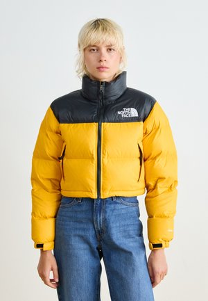 Dikke cropped jas met een gele body en een zwarte ritssluiting kraag. Kenmerken zijn een logo, zakken aan de voorkant en elastische manchetten.
