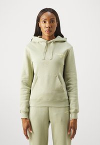 Sweatshirt capuz de algodão verde claro com um bolso canguru, apresentando discretos detalhes em logo dourado na parte da frente. Textura suave, corte casual.