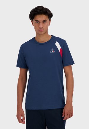 Marineblauwe katoenen T-shirt met een ronde hals, voorzien van rode en witte diagonale accenten op de schouder en een logo op de borst.