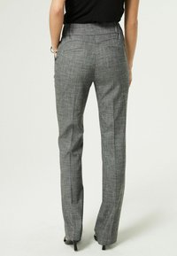 Grijze geruite trousers met een getailleerde taille, rechte pijpen, achterzakken en een gladde textuur. De broek wordt gedragen met hoge hakken.