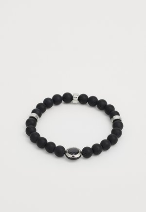Schwarze Perlenarmband mit glatter, matter Textur, verziert mit silbernen Akzenten und einem zentralen ovalen Detail. Einheitliches Design mit unterschiedlich großen Perlen.