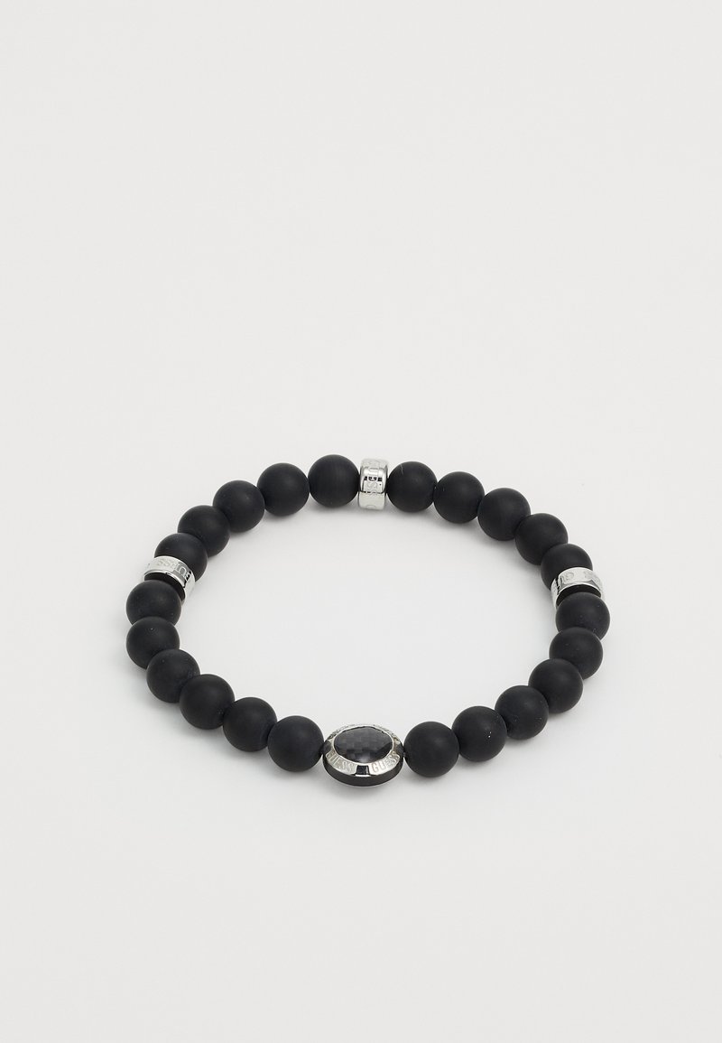 Bracelet en perles noires avec une texture mate lisse, mettant en avant des accents en argent et un détail ovale central. Design uniforme avec des tailles de perles variées.