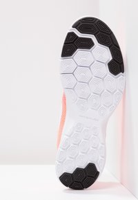 Semelle de chaussure Nike Flex présentant un motif hexagonal texturé noir et blanc, avec une touche de rose sur le côté pour un détail de design supplémentaire.