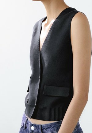 Gilet nero senza maniche con scollo a V, tessuto strutturato, chiusura frontale con bottoni e due tasche anteriori. Orlo inferiore a costine.