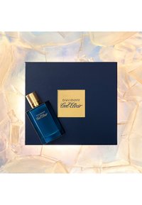 Davidoff Cool Elixir Duft in einer blauen Glasflasche mit goldenen Akzenten, daneben eine dunkelblaue Schachtel mit goldenem Logo und strukturierten Details.