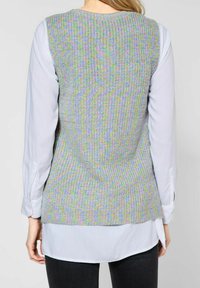 Knit vest in multicolor pastel hues (green, purple, yellow) with a textured pattern. Worn over a light blue collared shirt and black pants.