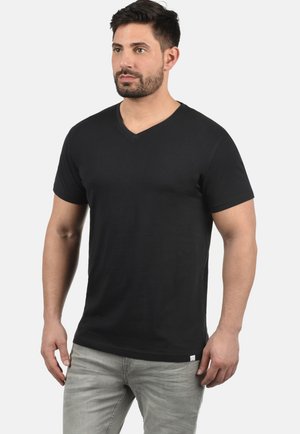 Black cotton short-sleeve T-shirt with a V-neck design, featuring a subtle texture and slightly fitted shape, paired with light gray pants.