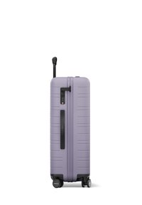 Valise rigide de couleur lavande claire avec des rayures verticales, une poignée rétractable et quatre roulettes fluides pour une mobilité aisée.