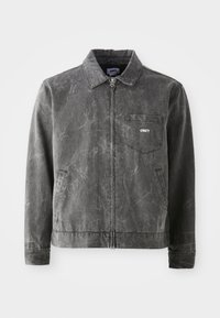Gray canvas jacket with a collar, front zip closure, and a left chest pocket. It features a subtle textured finish and side pockets.
