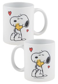 White ceramic mug featuring a graphic design of a dog holding a small bird, with red hearts on both sides. Smooth texture, curved handle.