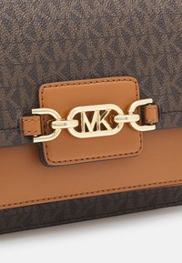 Bruine en tan handtas met een getextureerd monogrampatroon, een gouden MK-logo sluiting en gladde leren accenten.