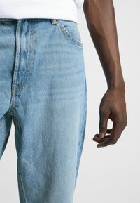 Ljusblå denimjeans med slim fit, med subtila whiskering, blekt utseende och kontrasterande sömmar vid fickorna.