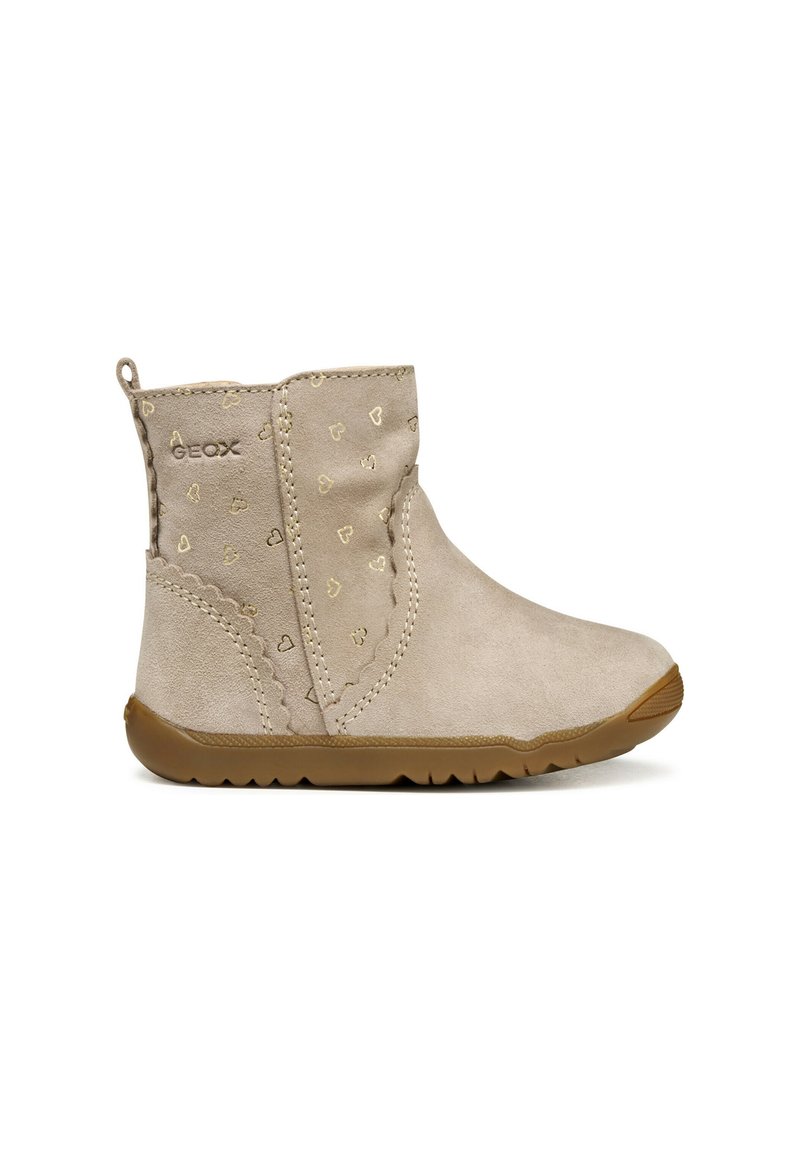 Botines beige de ante con un acabado texturizado. Presentan pequeños patrones de corazones dorados, una costura con volantes y una suela de goma flexible.