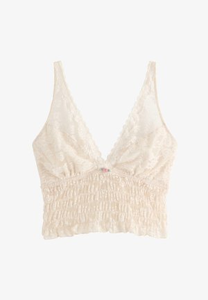 Kermanvärinen pitsinen bralette, jossa on rypytetty vyötärö, laskosreunat ja pieni vaaleanpunainen ruusukoriste keskellä edessä.