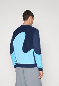 Sweatshirt masculino de gola redonda com um design em blocos de cor em azul marinho e azul claro, com acabamentos em tecido texturizado e um logótipo na bainha.
