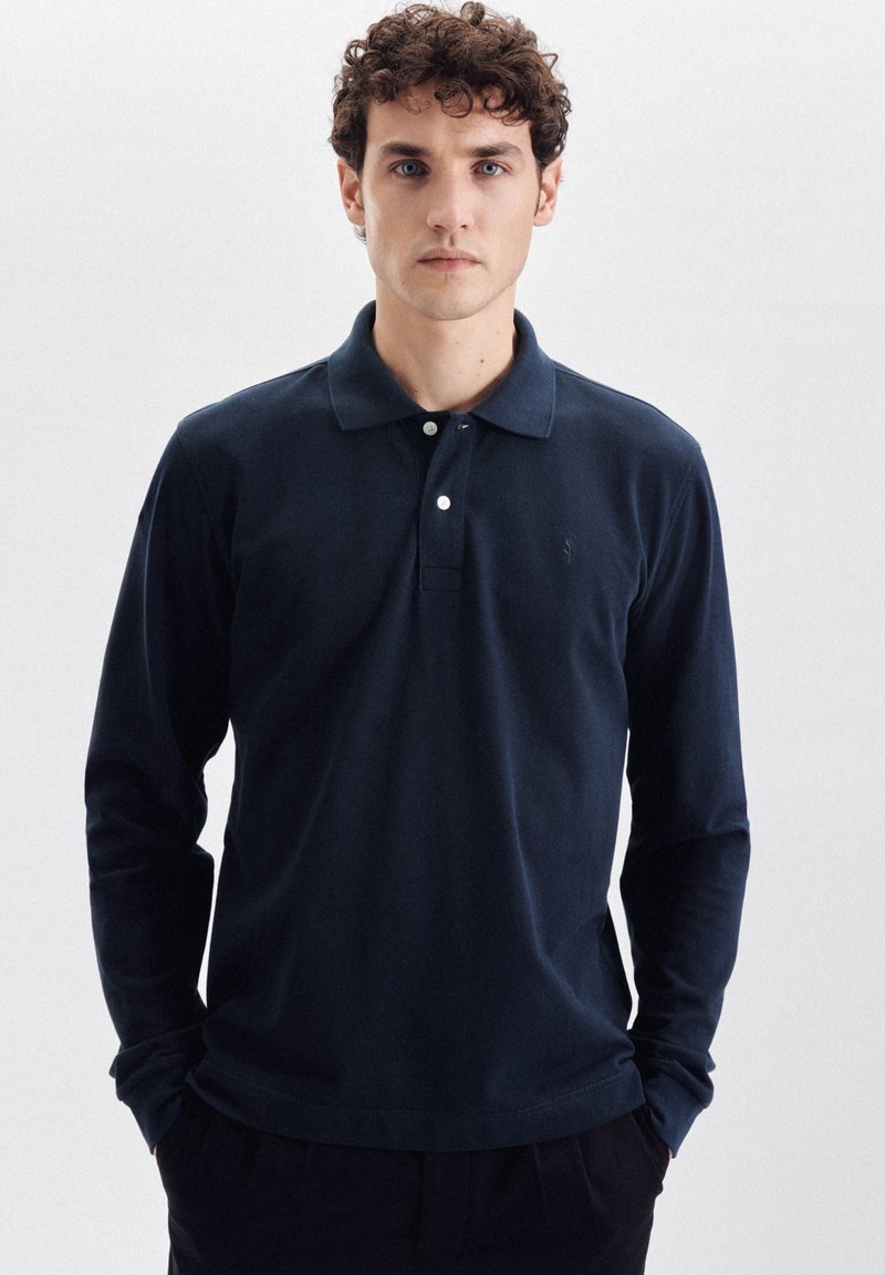 Polo a maniche lunghe blu navy realizzato in tessuto morbido, con colletto classico, mezza bottoniera a due bottoni e un logo discreto sul petto.