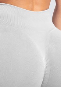 Lichtgrijze leggings met een ribbelstructuur, hoge taille en naadloos ontwerp. Heeft een taps toelopende pasvorm die de lichaamscontour accentueert.