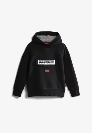 Persoon draagt een zwarte Napapijri hoodie en broek met een witte jas om de taille gestrikt, staand tegen een effen achtergrond.