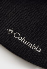 Czarna dziana czapka z grubym splotem i haftowanym logo "Columbia" w kolorze srebrnym. Prosty design, bez dodatkowych wzorów czy akcentów.