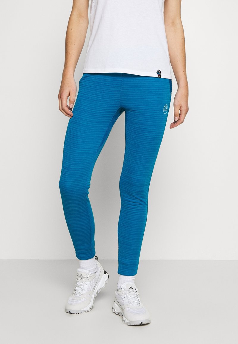 Turquoise leggings with a textured pattern, high-waisted design, and logo detail. Styled with a white t-shirt and athletic shoes.