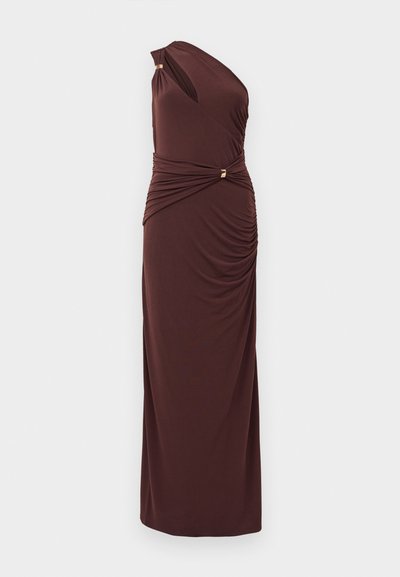 Asymmetrische bruine jurk van zachte stof, met gedrapeerde details bij de taille en accenten in goudkleurig metaal. Lange, nauwsluitende silhouet.