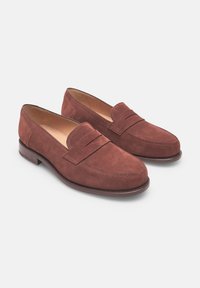 Mocassini in suede marrone caratterizzati da un design cucito con un dettaglio a fascia sulla parte anteriore, suole piatte e punta rotonda. Fodera interna liscia.