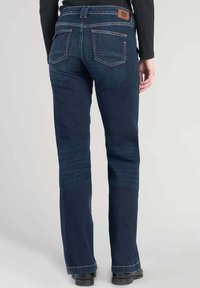 Mörkblå denimjeans med rak bendesign, fem fickor och en läderlogotyp på baksidan av midjebandet.