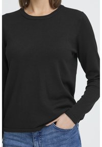 Pull noir à manches longues en texture côtelée avec un col rond. Présente des manches ajustées et une coupe décontractée au niveau du corps.