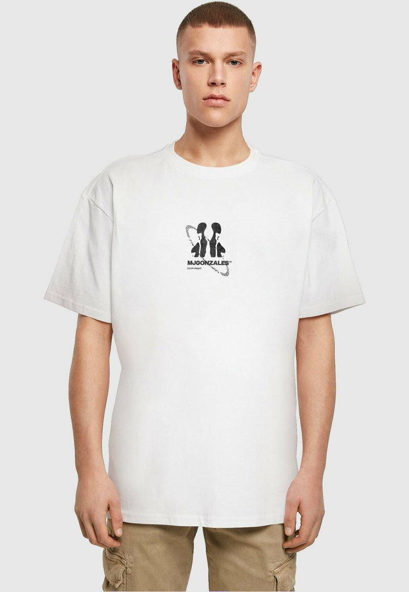 Hvid bomulds t-shirt med korte ærmer, der har et sort grafisk design i midten. Rund hals og afslappet pasform.