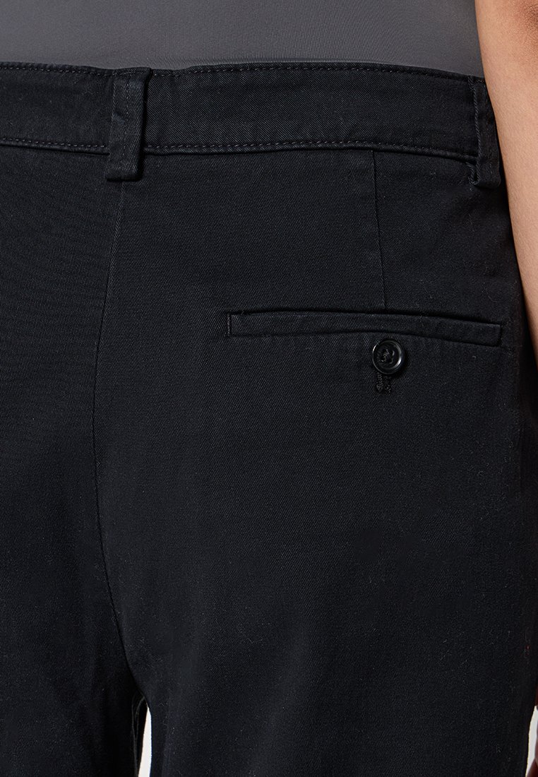 Schwarze, Baumwollmischung-Hosen mit schmaler Passform, ausgestattet mit einer Gesäßtasche mit Knopfverschluss und zarten Steppnähten entlang des Taillenbunds.