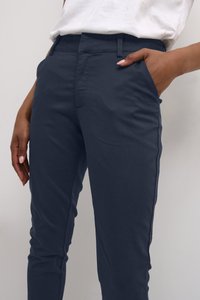 Marineblaue Hose aus weichem Stoff, mit schmaler Passform, seitlichen Taschen und einer glatten Textur mit minimalen Nähten.