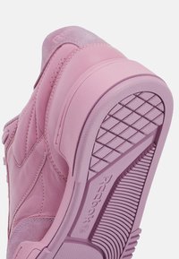 Light pink sneaker featuring smooth leather and suede uppers, textured outsole with a diamond grip pattern, and contrasting stitching details.