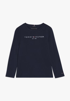 Navy blue long-sleeve shirt with "Tommy Hilfiger Est. 1985" text and small logo flag on left sleeve cuff.
