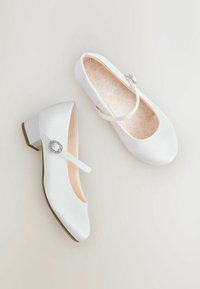 Hvide satin sko med lukket tå og en lille hæl. De har en strop med en dekorativ spænde og en blød, lys rosa indersål.