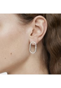 Orecchini d'argento a forma ovale allungata, con una finitura metallica liscia e una chiusura sicura per mantenerli in posizione.