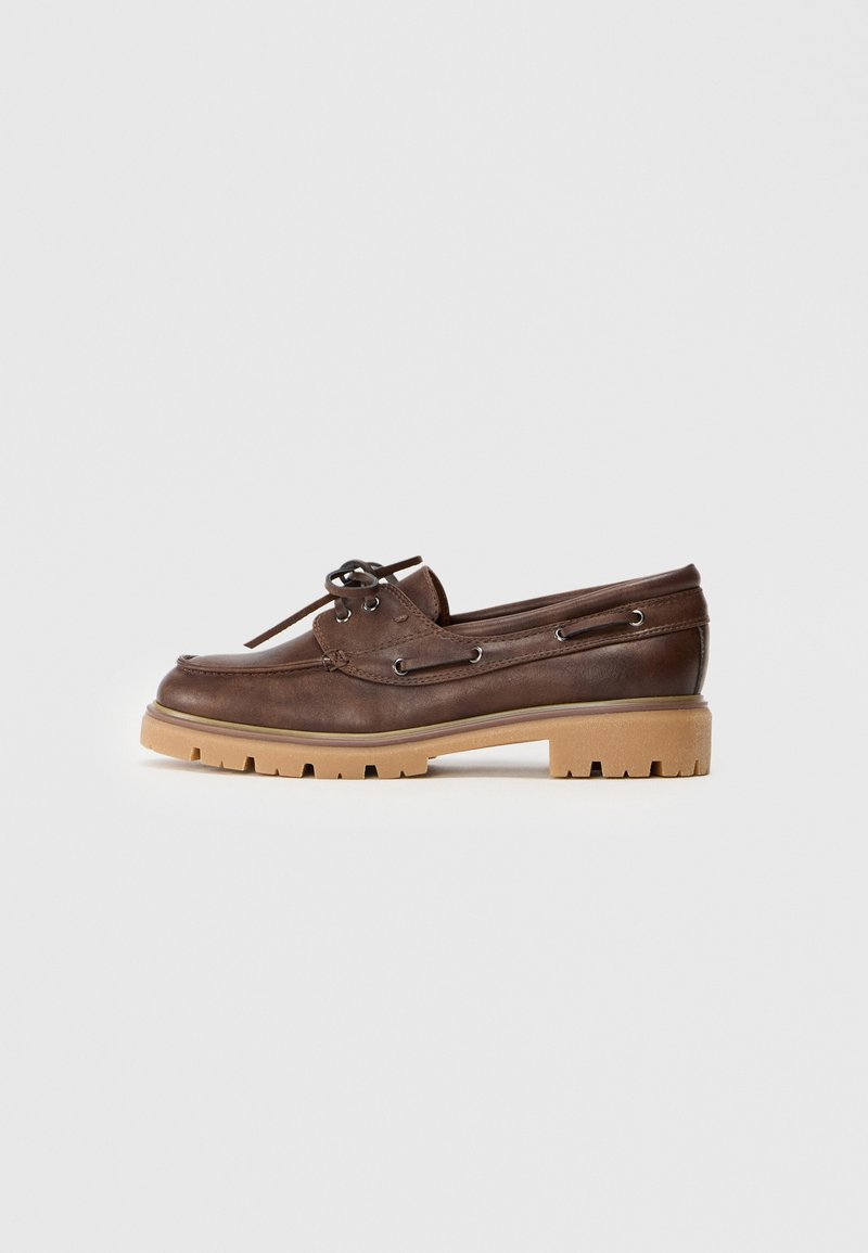 Καφέ δερμάτινο παπούτσι σκάφους με στρογγυλή μύτη, λεπτομέρειες από κορδόνια και αντίθετη καφέ καουτσούκ σόλα, η οποία διαθέτει υφή και σχέδιο στην επιφάνεια.