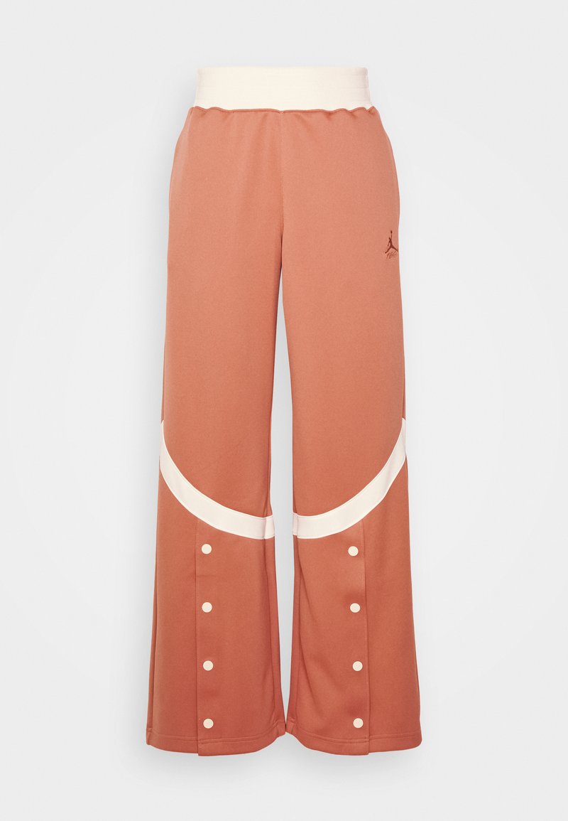 Pantalons larges couleur pêche avec une taille élastique blanche, présentant des accents courbés blancs et des détails à boutons-pression sur les côtés.