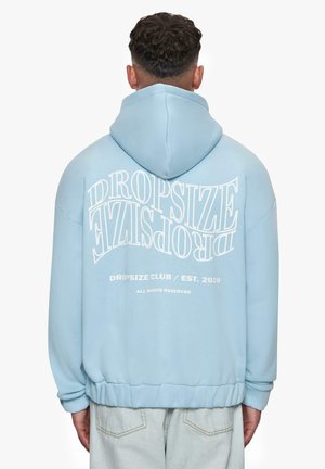 Light blue oversized hoodie with a drawstring hood, featuring large white text on the back and ribbed cuffs, in soft cotton material.