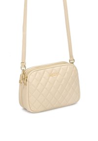 Borsa a tracolla trapuntata beige con chiusura a zip e hardware dorato. Presenta una sola tracolla e il nome del marchio impresso davanti.