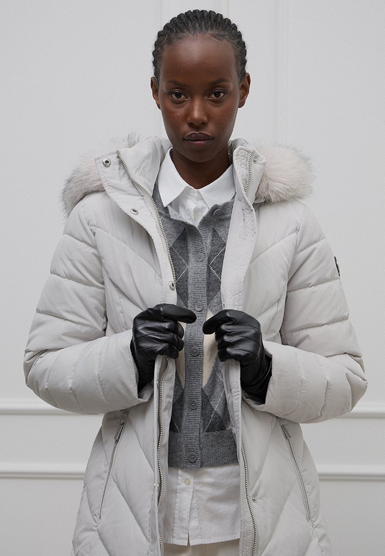 Jasnoszara kurtka puchowa z kapturem z sztucznego futra, ściągaczami na mankietach i z zapięciem na zamek. Nosi się ją na szarym swetrze w romby i białej koszuli z kołnierzykiem.