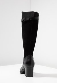Czarne kozaki za kolano z zamszowej cholewki, skórzanymi akcentami, okrągłym noskiem i niskim obcasem blokowym. Zawiera boczny pasek z detalem klamry.